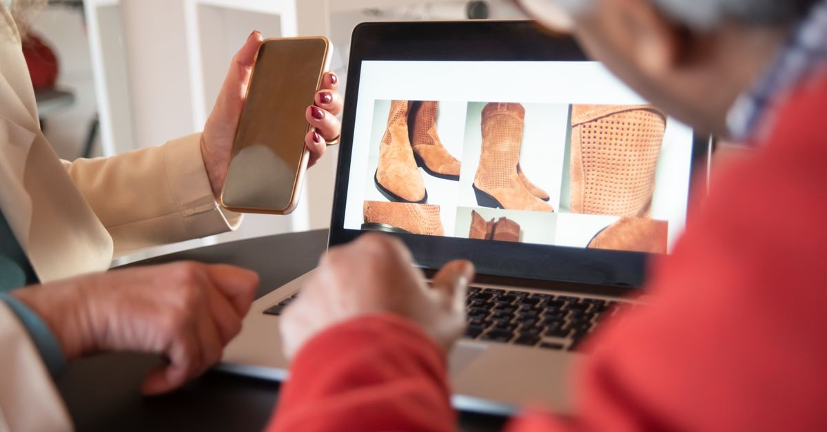 Two people shopping for shoes online using a laptop and smartphone at home.